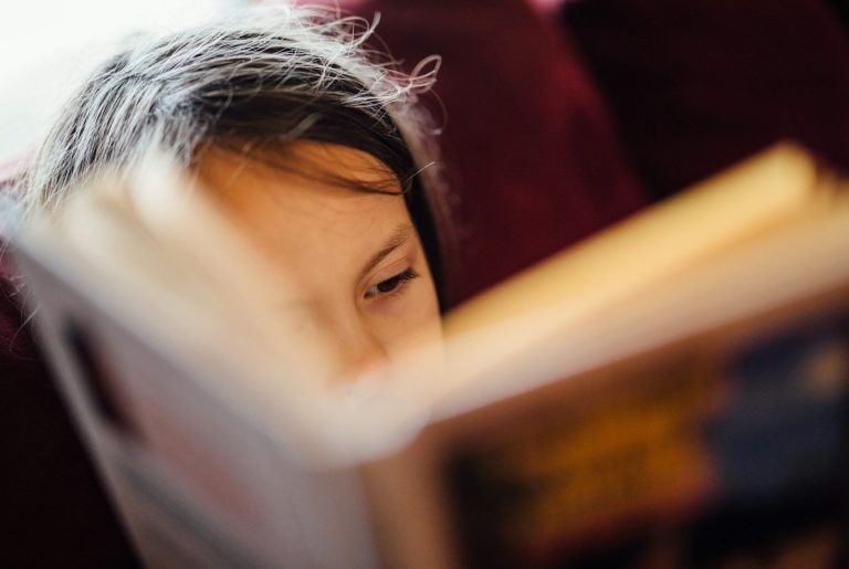 Child reading a book, with focus on their eyes and the open pages.