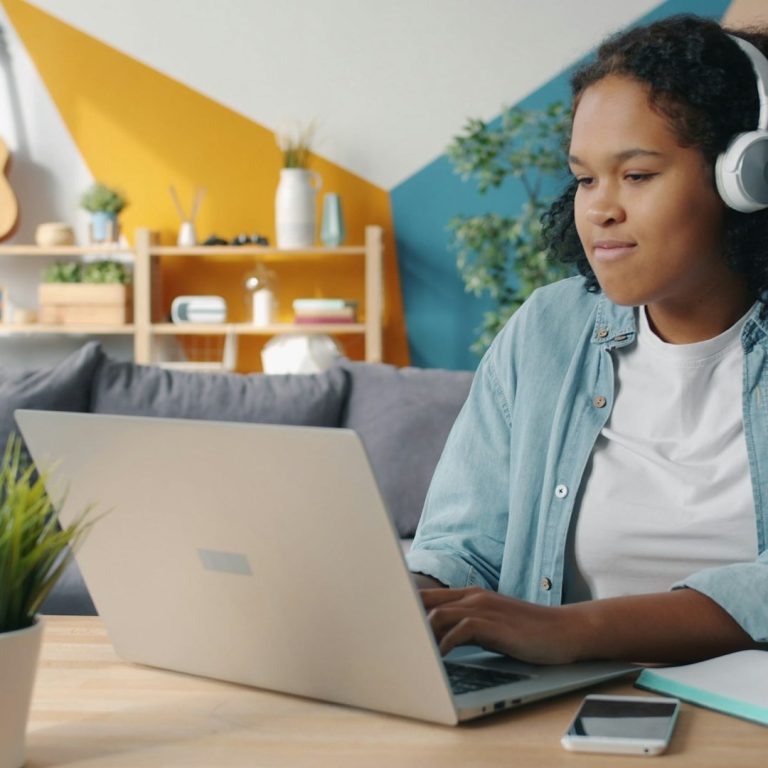 Working on a laptop Young woman wearing headphones, working on a laptop in a stylish, modern room.