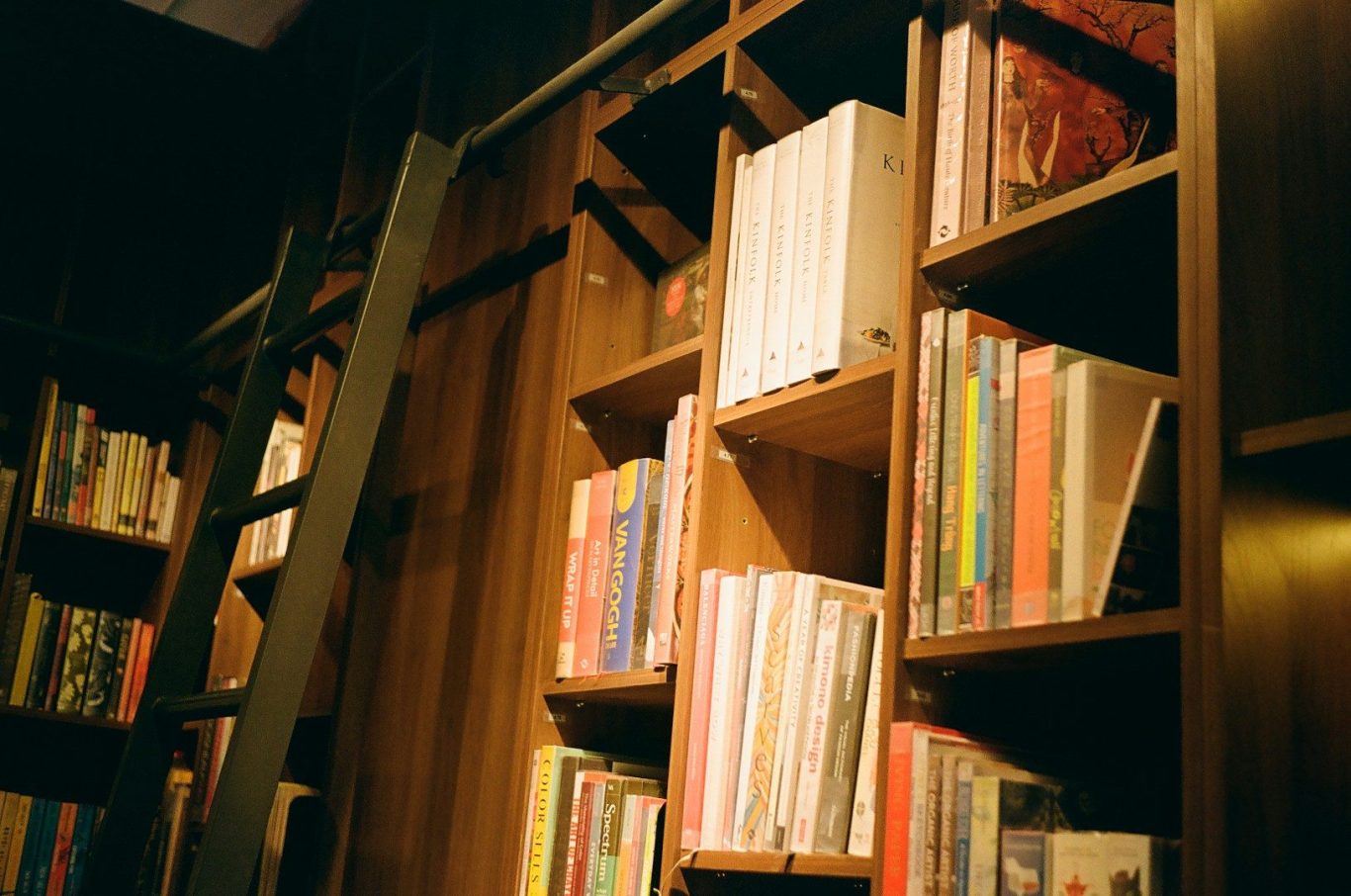 Bookshelves Bookshelves filled with various books, featuring a wooden ladder for access.