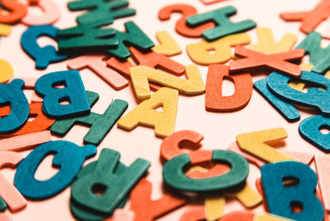 Letters Colourful wooden letters scattered on a light background.